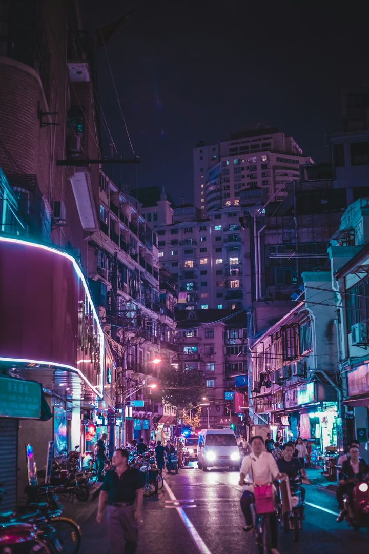 People walking through a neon-lit Shanghai street at night